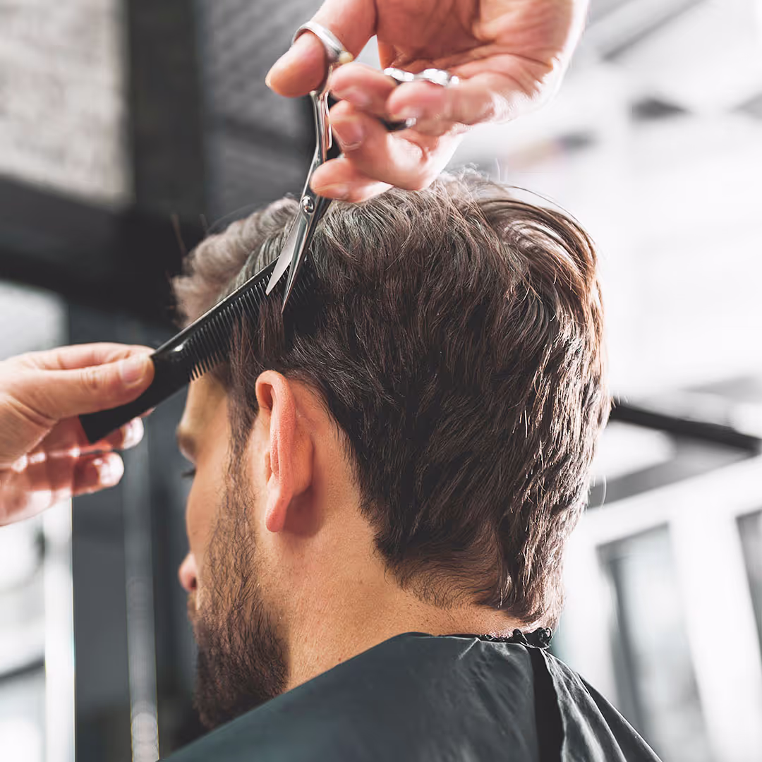 Ein Mann beim Friseur. Man schneidet ihm die Haare.